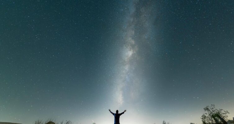 a man standing under a starry night sky